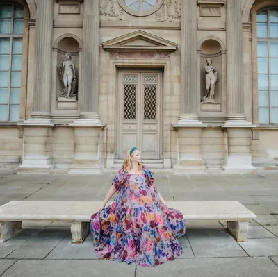 Rachel Murphy in a flowing floral dress at a European palace courtyard